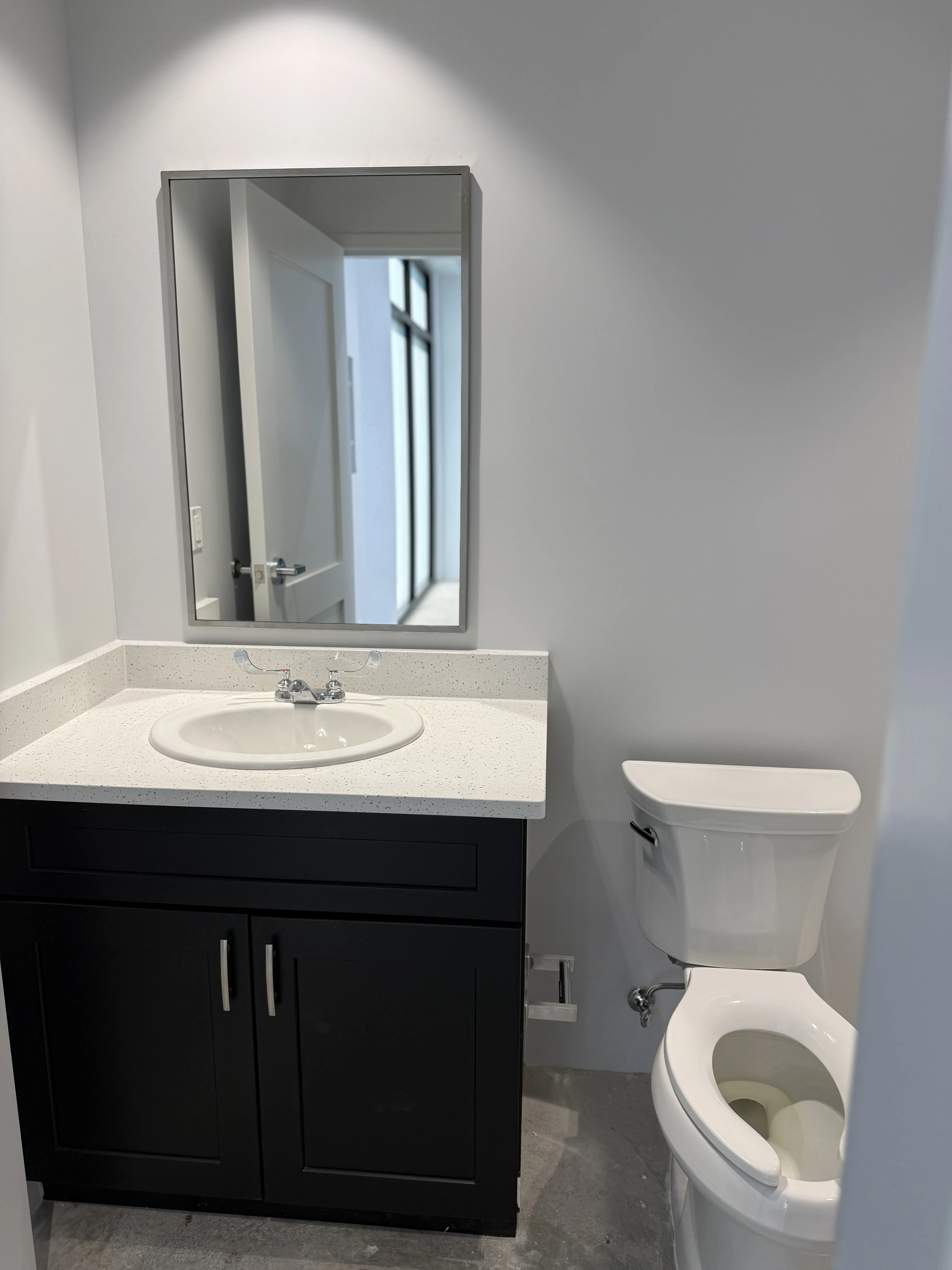 Bathroom with black vanity, quartz countertop, mirror, and toilet