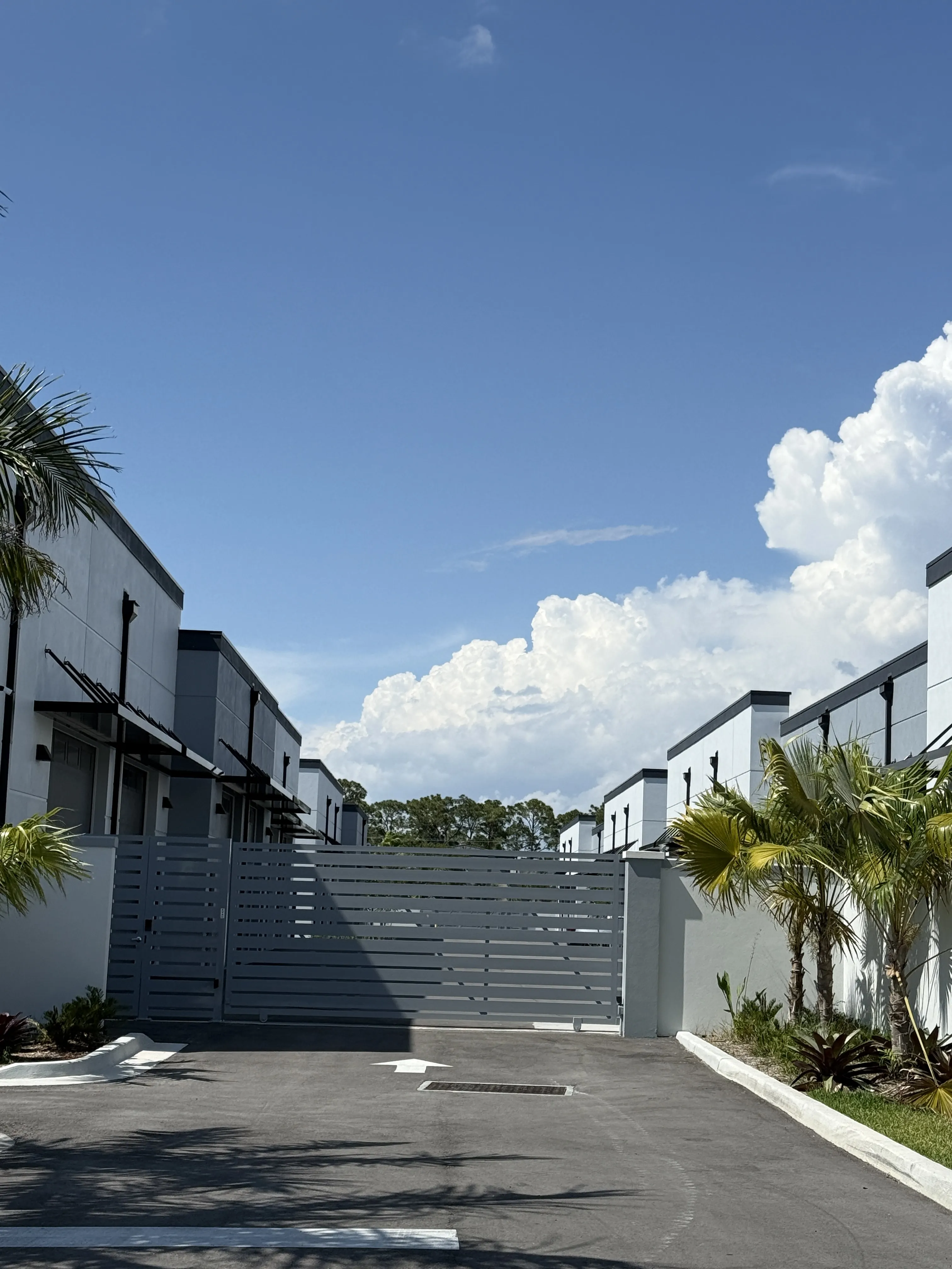 Gated entrance with row of units and palm trees