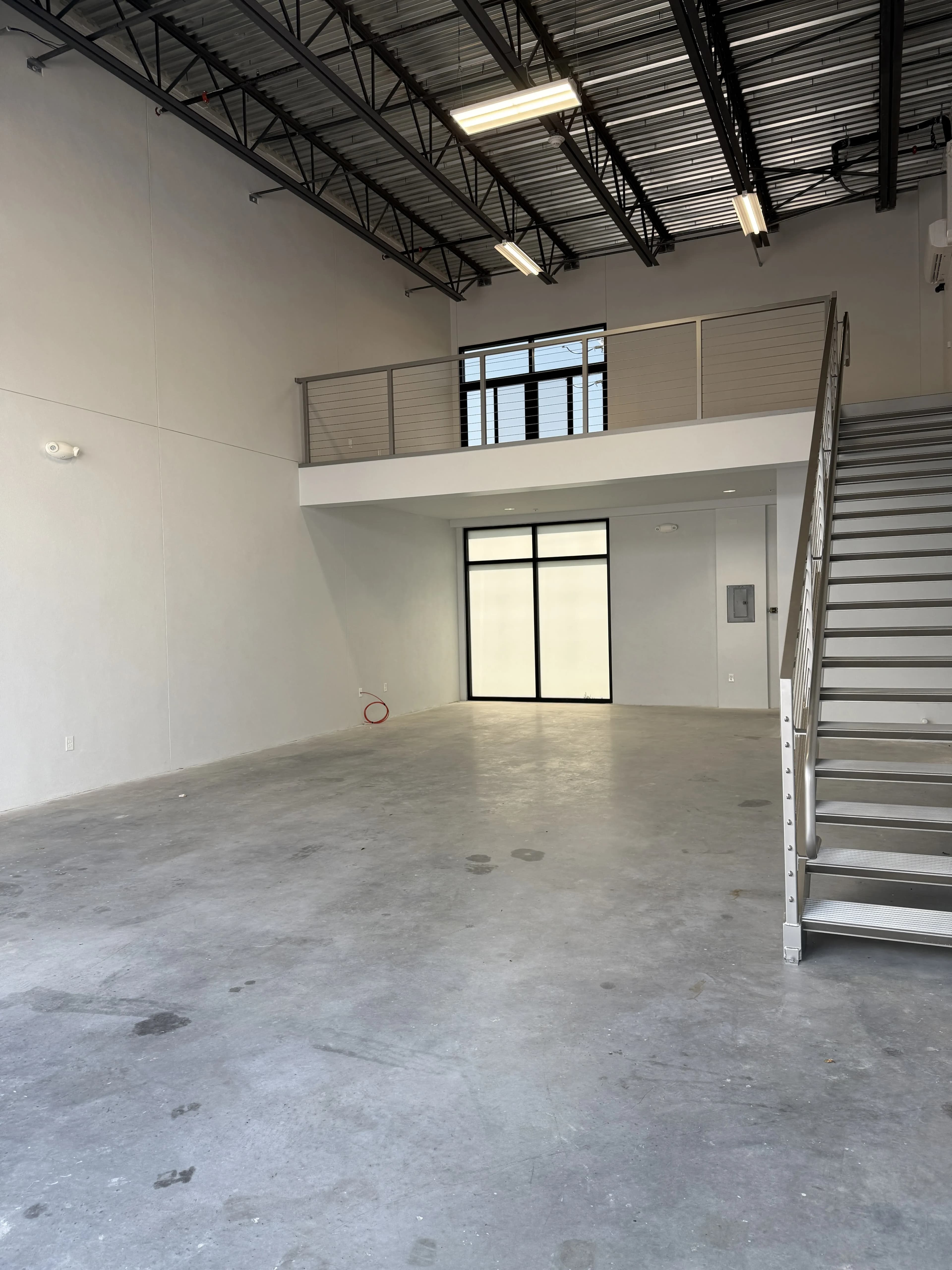 Wide view of garage floor with mezzanine, staircase, and glass entry door
