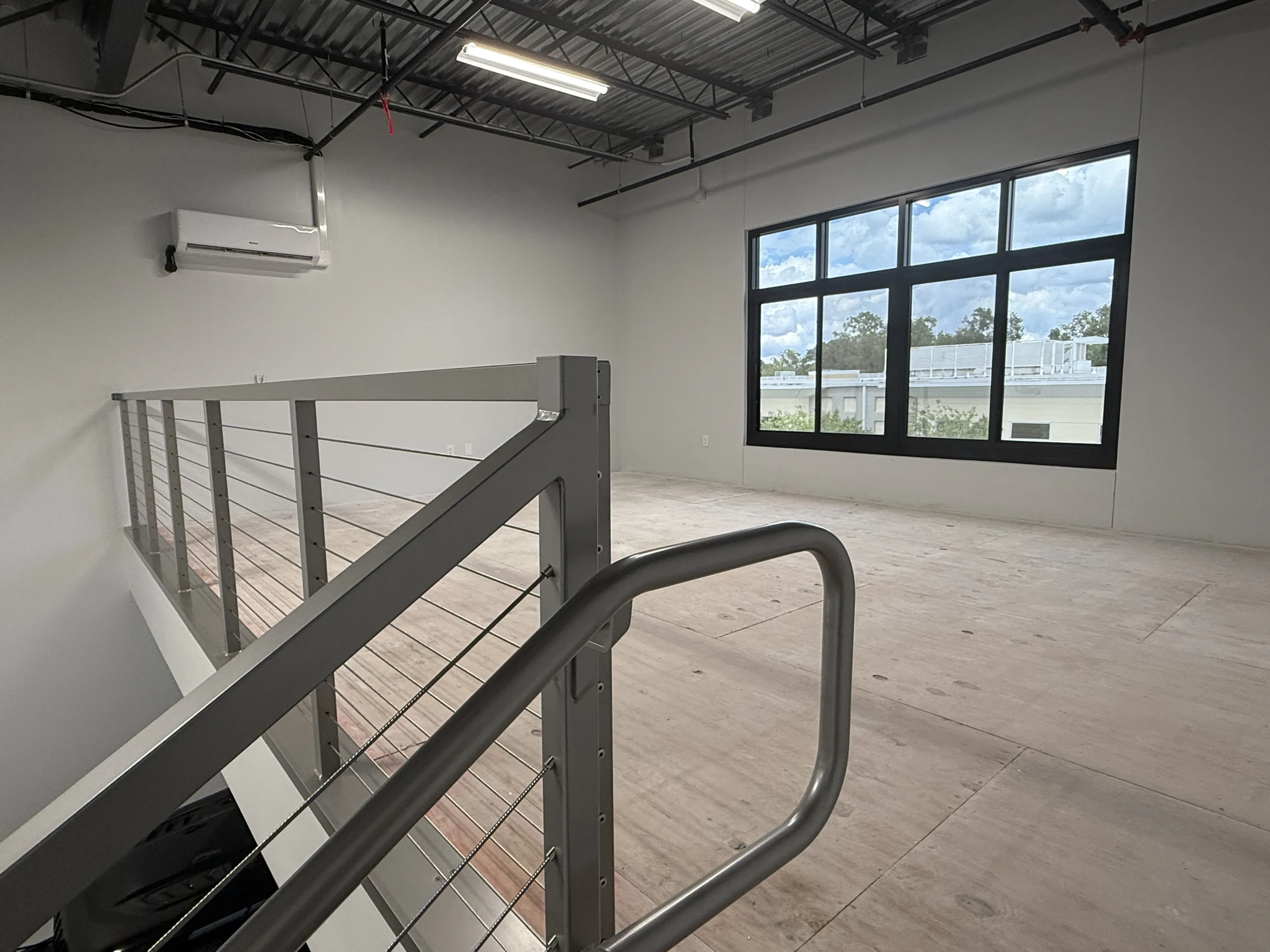 Mezzanine level from top of stairs with cable railing, windows, and mini-split AC